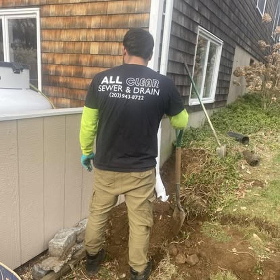 All Clear Sewer & Drain technician digging beside a house